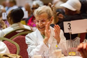 A seated woman attending Senior Connection applauding