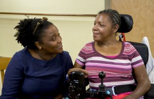 An Adult Disability Services staff member talking with an individual in a wheelchair